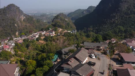 una carretilla aérea que revela a un motociclista cruzando el pueblo rural de pha mi en las tierras altas de tailandia