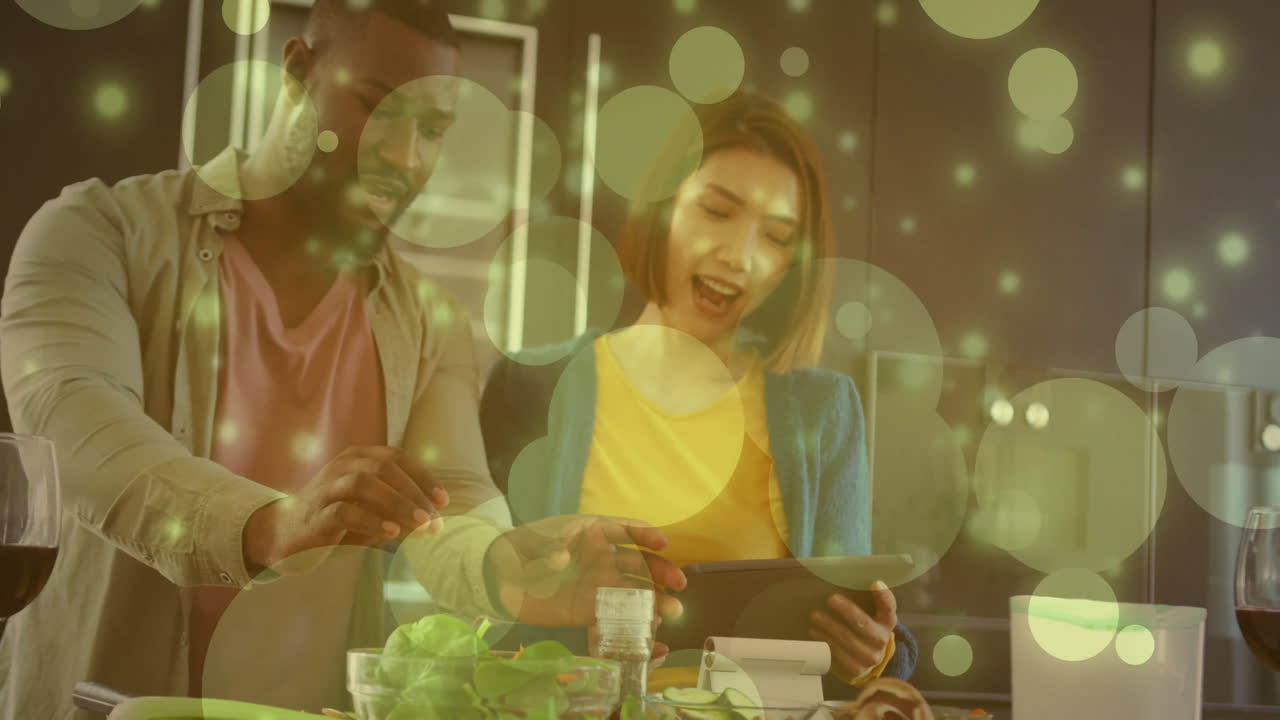 부에서 함께 요리하는 커플, 녹색 거품 애니메이션으로 태블릿을 사용하는 커플