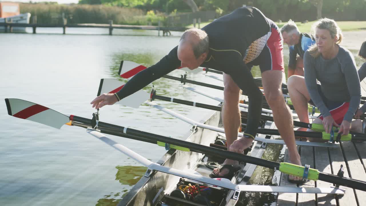 Four senior caucasian men and women preparing rowing boat in a river