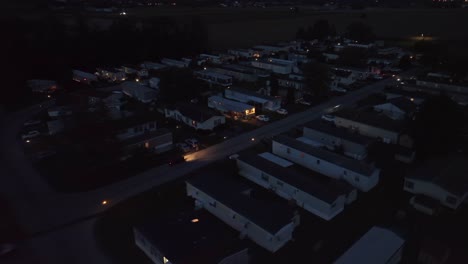 night falls on a mobile home park with lit windows, quiet streets