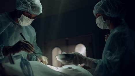 african american surgeon operating patient in sterile hospital emergency room.