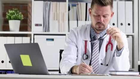 joven médico escribe datos médicos del paciente en la tarjeta en el lugar de trabajo película en 4k en cámara lenta