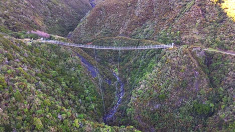 flying next to a large swing bridge over a steep valley