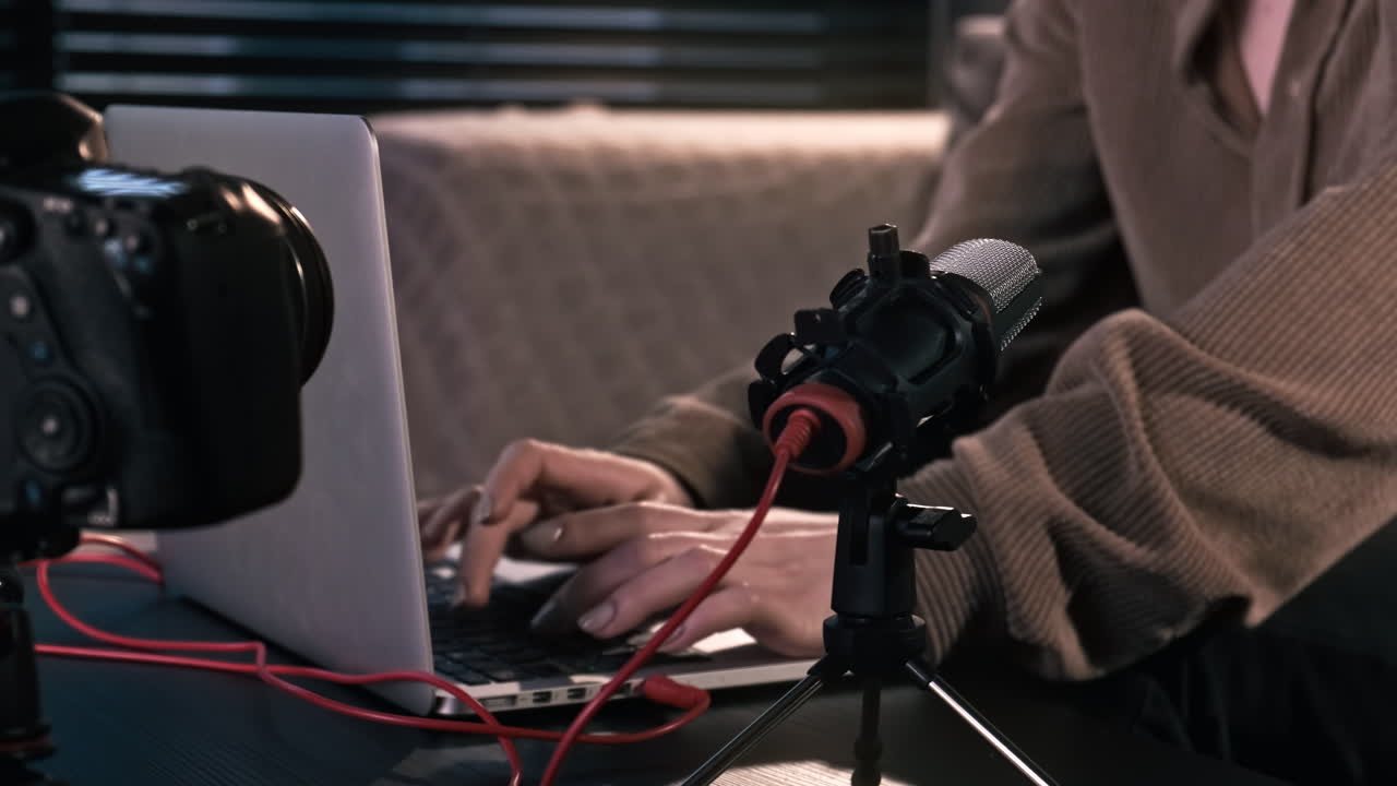 Young content creator girl working on her laptop on the table with camera on a tripod, microphone. Working from home
