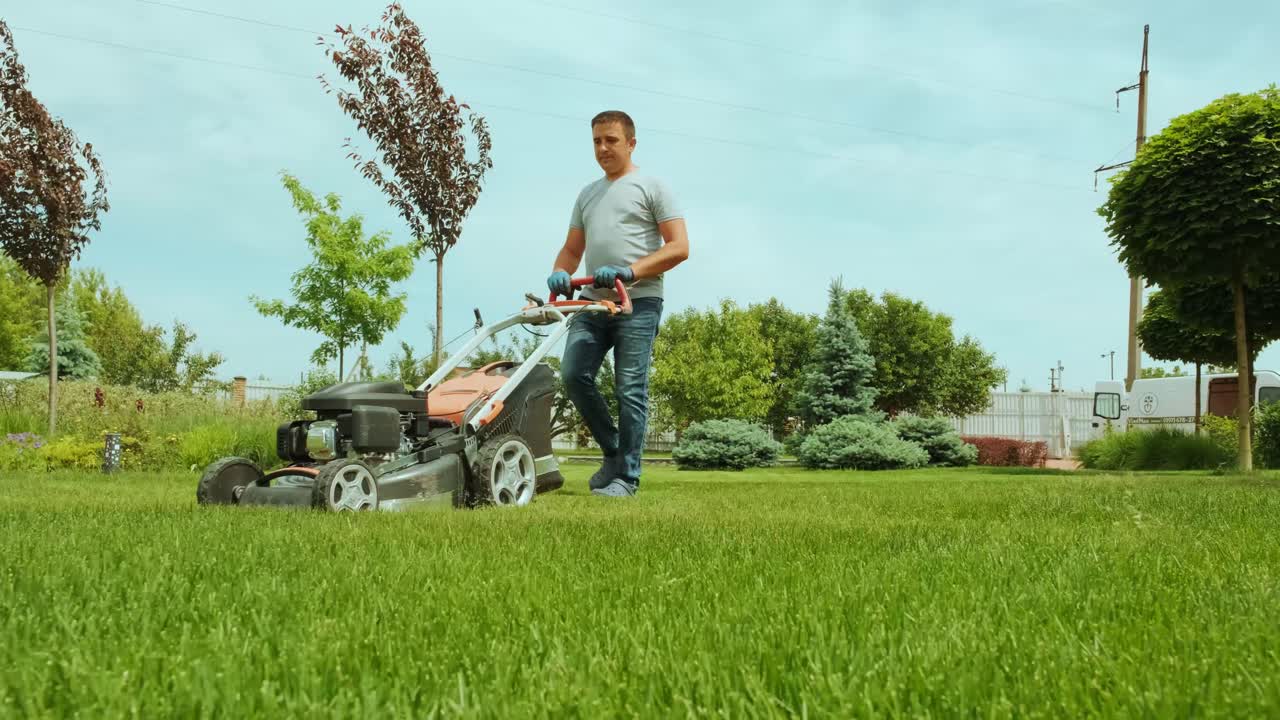잔디를 는 잔디 기. 정원 활동. 빛 정원에서 가솔린 구동 잔디기와 함께 잔디을 는. 정원에서 잔디 자르기 기계와 함께 일하는 정원사. 잔디자리 기