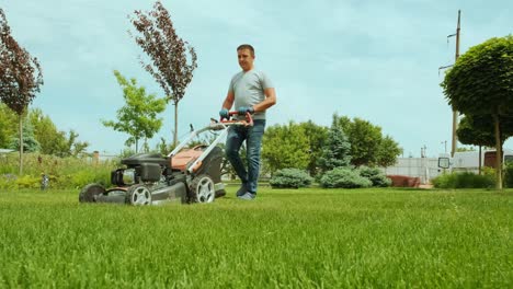 lawn mower cutting the grass. gardening activity. cutting grass with petrol driven lawn mower in sunny garden. gardener working with  mower machine in the garden. lawn mower cutting green grass