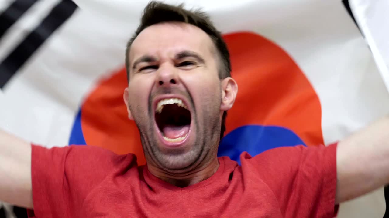 un fanático surcoreano celebra sosteniendo la bandera de corea del sur en cámara lenta, 4k, de alta calidad