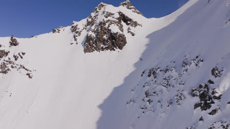 aerial footage of the iconic freeride paradise of verbier on a stunning bluebird day. snow-covered peaks, wide open faces, and legendary off-piste terrain under clear alpine skies