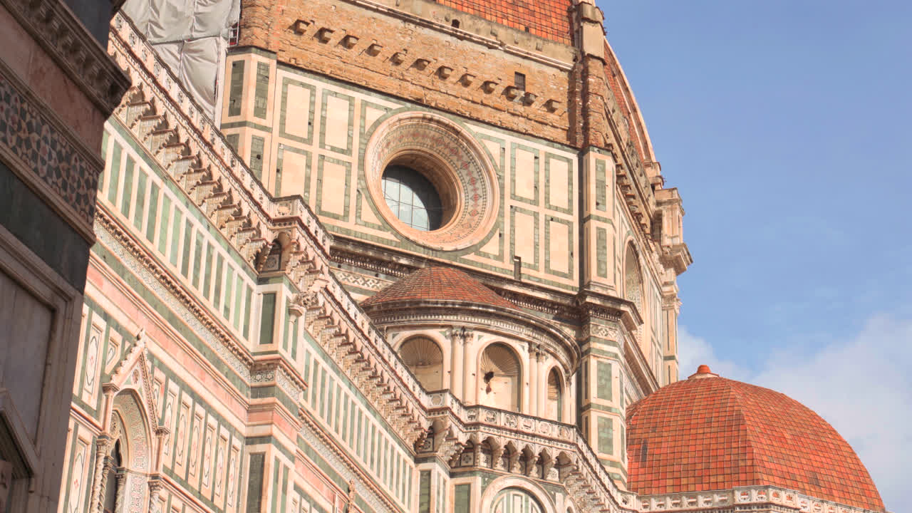 Cathedral dome and campanile rising above rooftops of Florence under clear blue sky in renaissance city