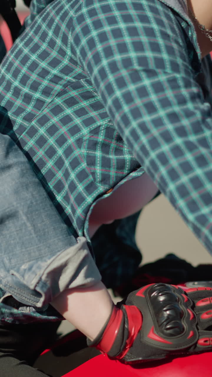 도시 도로를 가로질러 빨간색 전력 자전거를 타고 지나가는 두 여인, 건물과 차를 배경으로 지나가며, 그들의 옷이 움직일 때 날아갑니다.