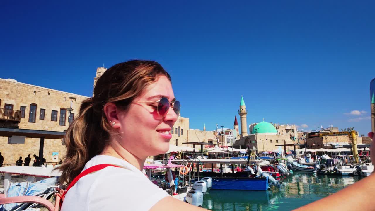 Turista donna che scatta una foto verticale di moschea e porto