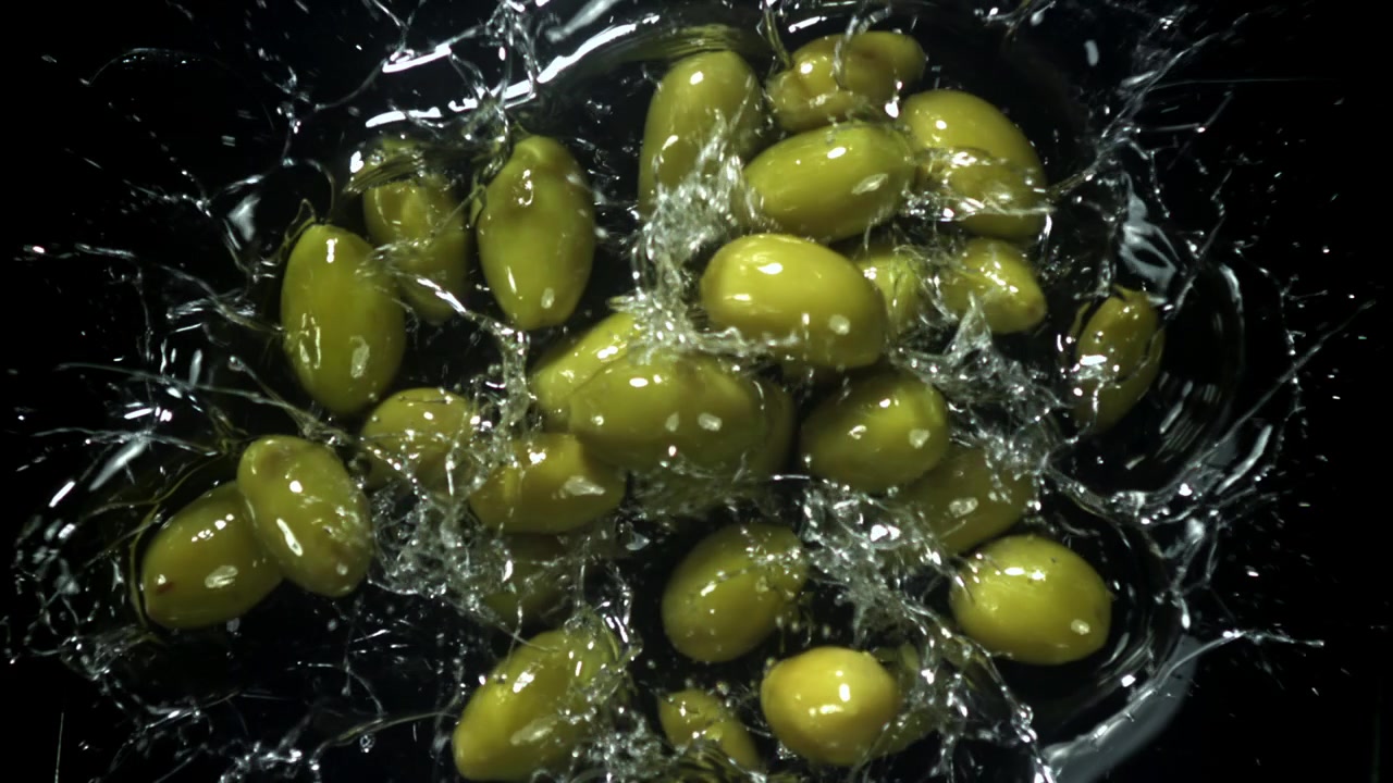 Olive verdi che schizzano nell'acqua al rallentatore