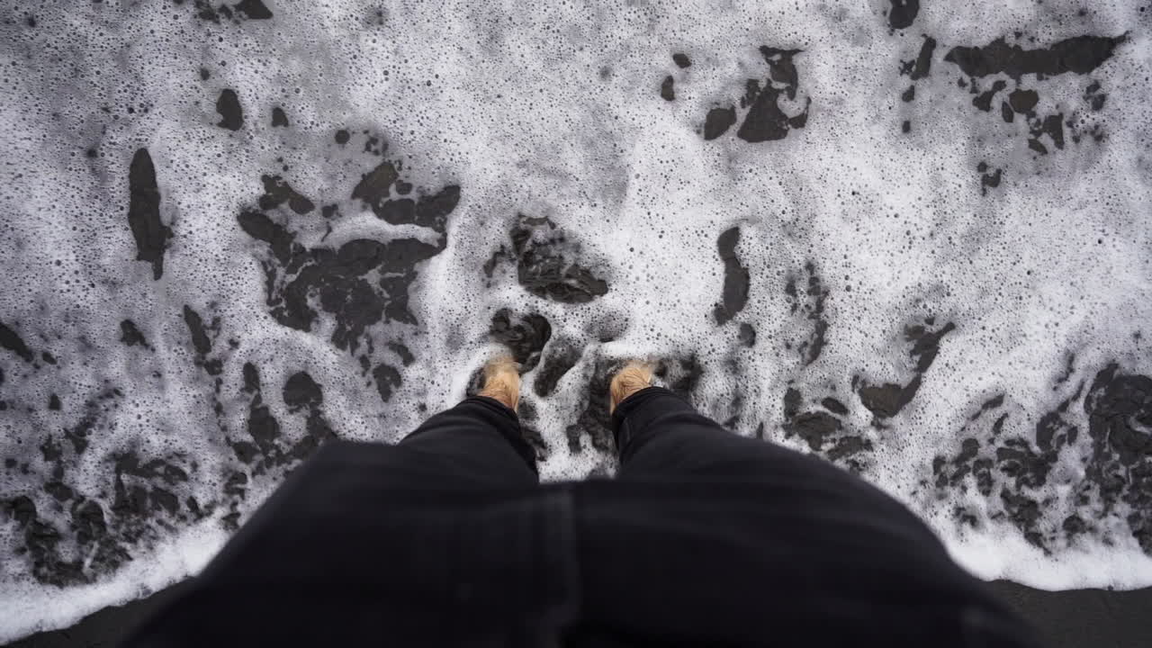 Sinking feet in black sand and Tenerife Benijo island Spain waters pov