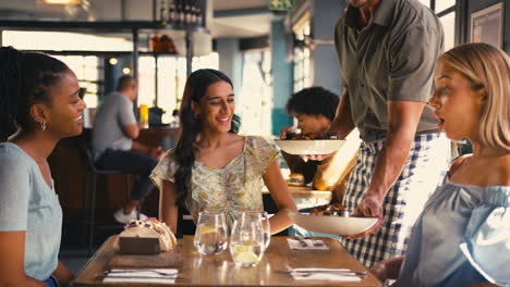 group of female friends meeting up in restaurant being served meal