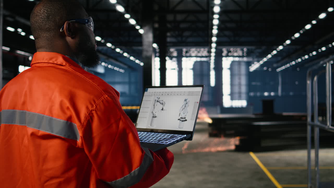 African american technician reviews robot software model on laptop