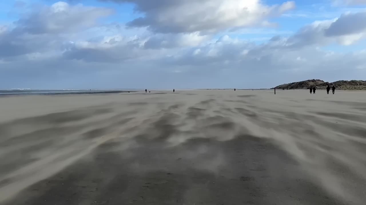 шторм на побережье, люди ходят по пляжу через смещающийся песок