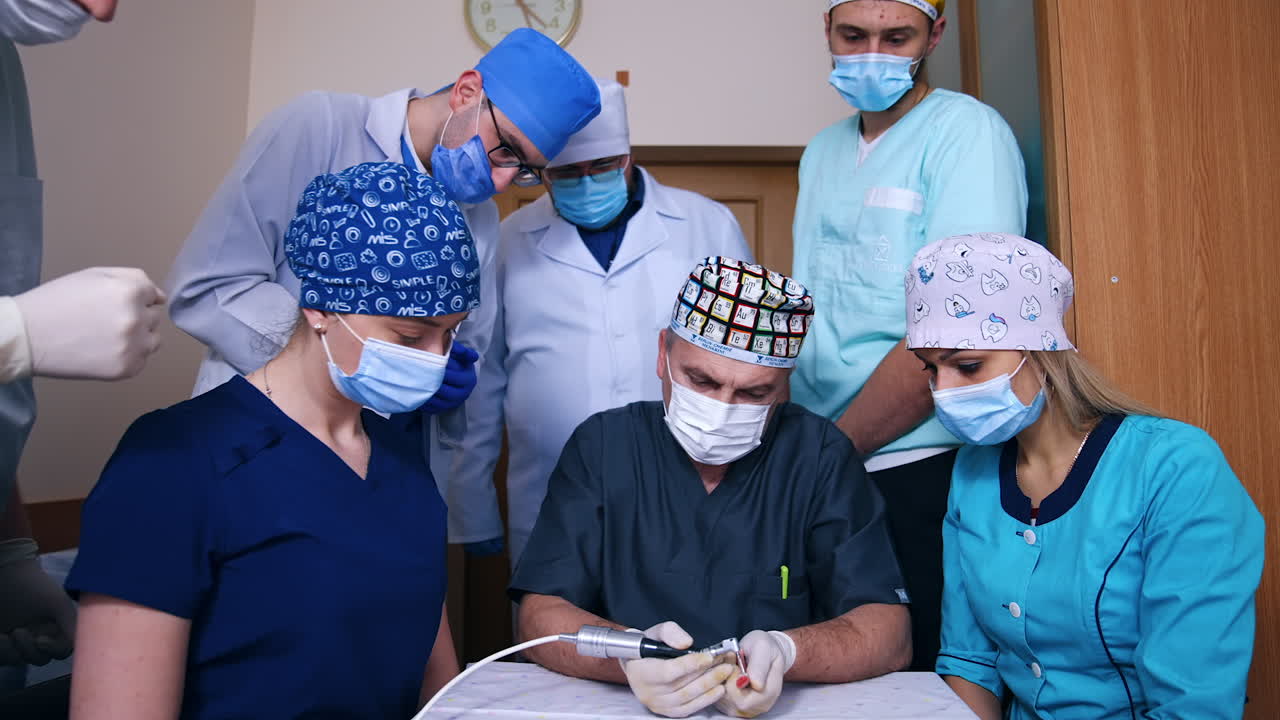 Ortodoncista enseñando sus habilidades a los estudiantes. Futuros dentistas observan atentamente alrededor