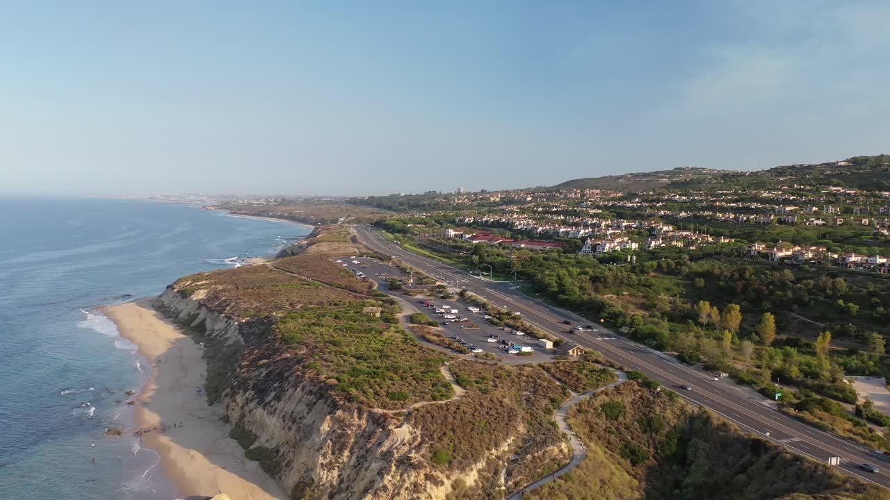 потрясающая съемка с беспилотного летательного аппарата с разрешением 4 k, пролетающего над океаном, где роскошные дома смотрят на разбивающиеся волны в прекрасный солнечный день в округе оранж