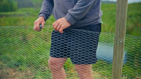 a man with a plier tool installing a wire mesh fence. close-up shot