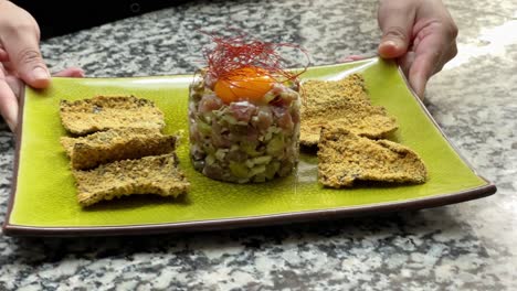 presenting tuna tartare dish in a kitchen counter