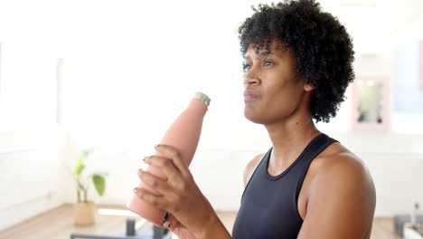 biracial female yoga instructor holding small bottle