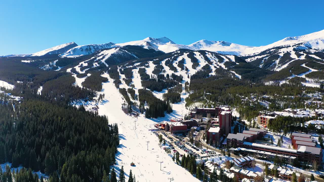 vista aérea por drones de pistas de esquí nevadas con telesilla con vistas a hermosos picos montañosos en breckenridge, colorado, con casas de montaña y alquileres vacacionales