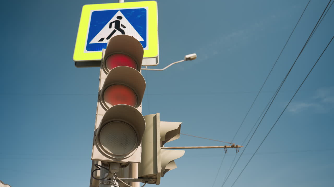 vista cercana de un semáforo que cambia de rojo a verde, situado cerca de una señal de cruce de peatones, captura elementos de la calle urbana y la transición de las señales de tráfico