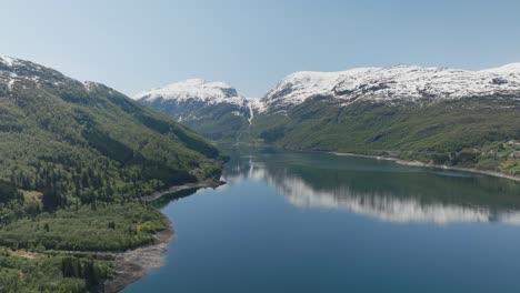 Atemberaubende-Luftaufnahme-Eines-Ruhigen-Fjords,-Umgeben-Von-Schneebedeckten-Bergen-Und-üppigem-Grün