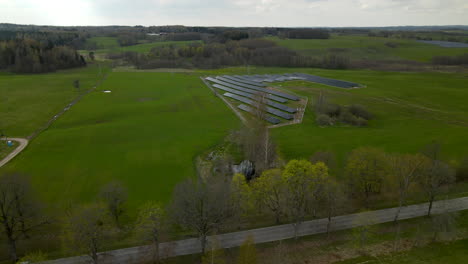 4k drone shot of cars driving on rural road beside solar panel farm on countryside fields in poland