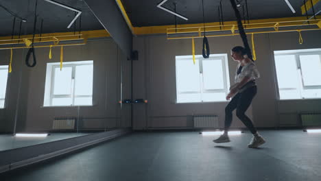 woman is doing exercise in gym practicing suspension training modern sport activity for keeping fit