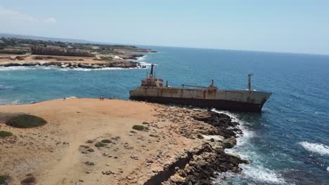 aerial drone shot of a big broken ship, stranded on a rocky coast