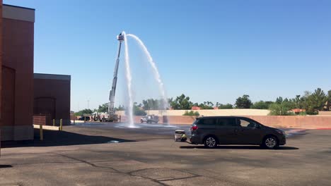 As-a-minivan-passes-by-,-two-streams-of-water-gush-out-of-firehoses-located-on-top-of-the-extended-ladder