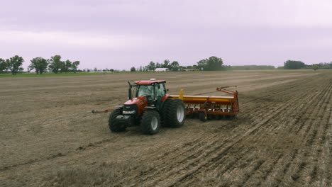 aerial - harvester tractor cultivating land, agriculture field, spinning shot