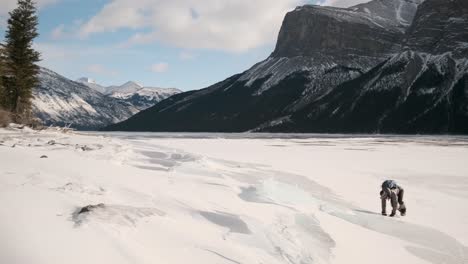 Girl-Hiker-Enjoys-Sliding-Down-Ice-Slab-in-Beautiful-Winter-Mountains-on-the-Frozen-Lake-Minnewanka-in-Banff-National-Park-Alberta-Canada-on-a-Sunny-Outdoor-Day