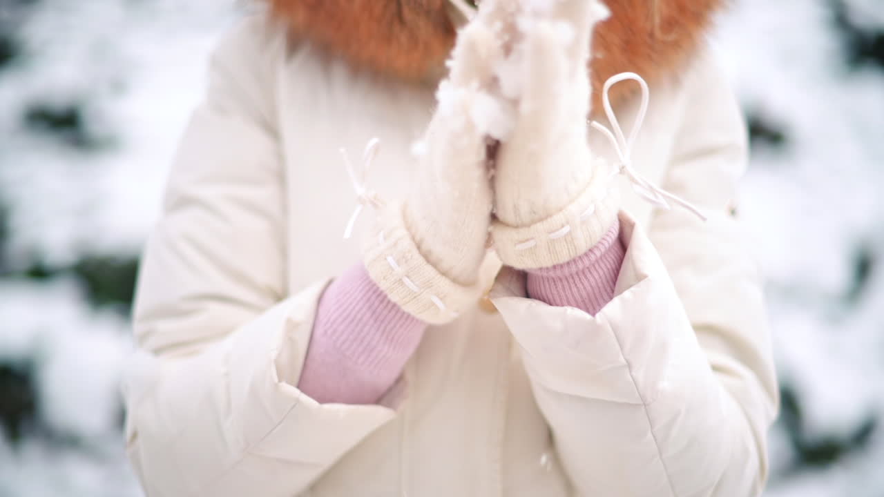 Two hands clad in warm gloves playfully gather fresh snow in a serene winter landscape. Soft snowfall provides a magical atmosphere in a peaceful outdoor space