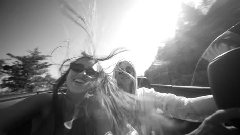 two women enjoying a joyful convertible road trip in black and white