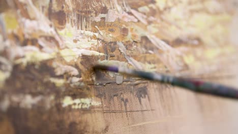 lightly and slowly brushing painting with green paint brush extreme close up