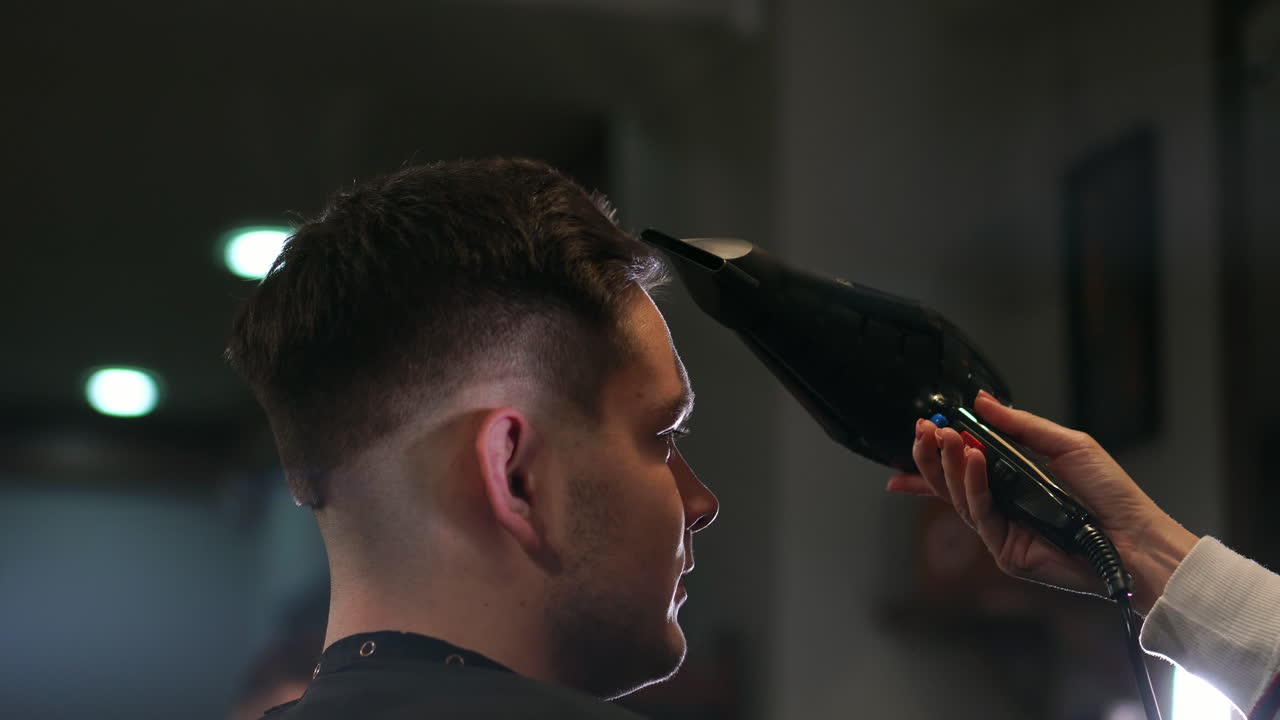 peinado masculino en el salón. hombre secando el cabello en la barbería. barbero peinando el cabello con secador. terminar la peluquería. secador de cabello hombre en la barbería