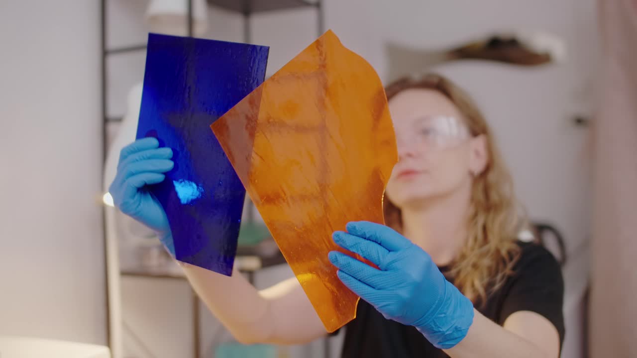 Woman holding blue and orange stained glass sheets