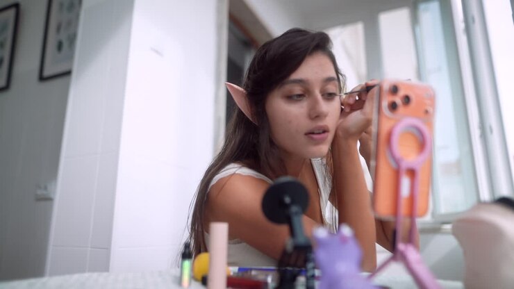 Ung kvinde med elverører lægger makeup til en tutorial.
