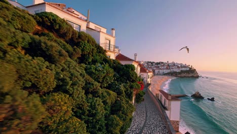 aerial video captures a scenic coastal village at sunset, showcasing stone houses and a winding