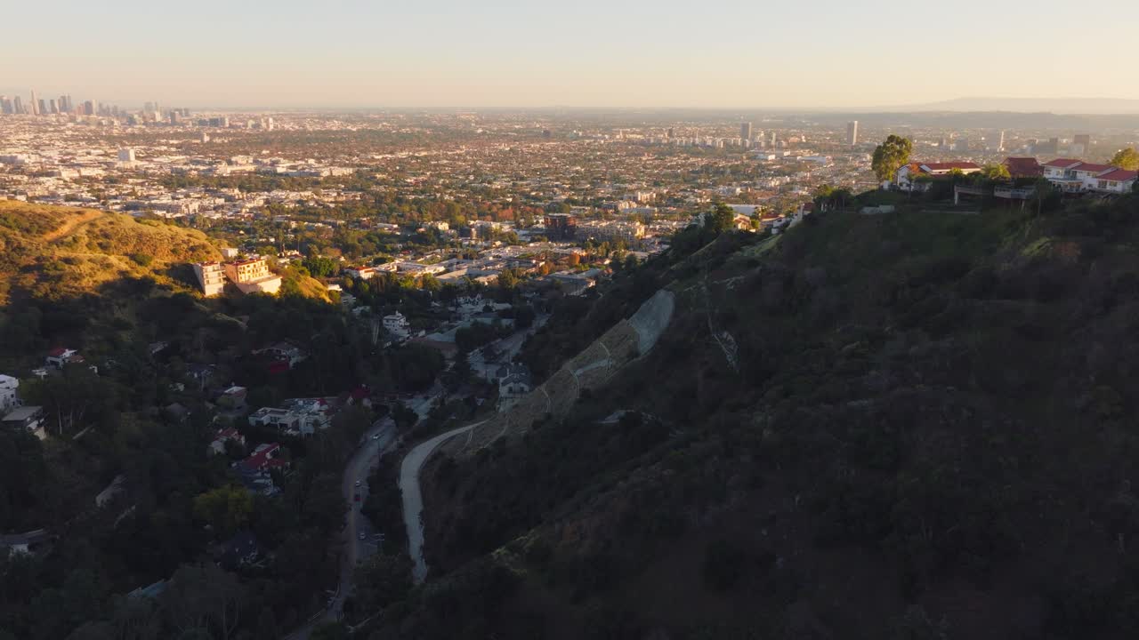 Drone che vola lentamente sopra le montagne a Runyon Canyon a Hollywood, California, con sentieri sottostanti e la città in lontananza.