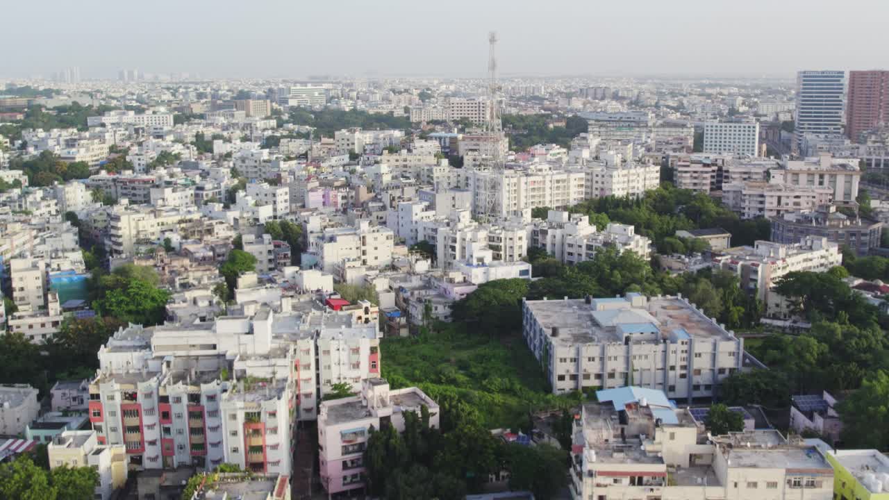 Filmato aereo cinematografico di una città indiana che mostra da vicino un'enorme torre antenna e gli edifici.