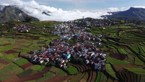 Cinematic-drone-shot-of-Poombarai-village-on-Palani-hills-with-clouds-approaching-the-valley,-Terrace-farming-landscape-in-mountains,-Tamil-Nadu,-India