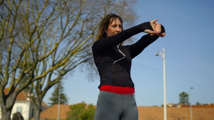 Beautiful focused sportswoman exercising in park