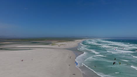 kitesurfer glides across ocean waves along the wide beach of hermanus, western cape, sa
