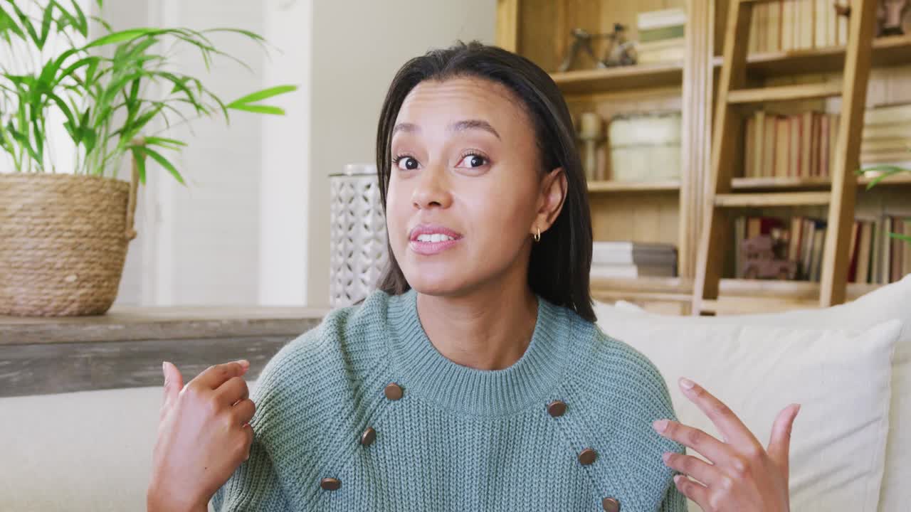 Happy biracial woman sitting on sofa and having video call, in slow motion