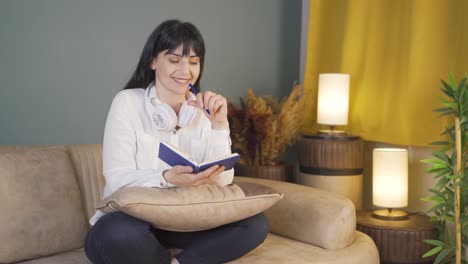 happy woman at home at night keeping a diary. woman both thinks and writes.