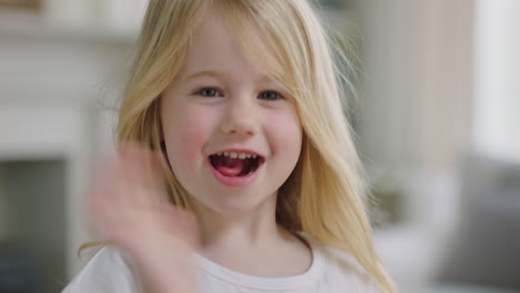 Retrato-Hermosa-Niña-Con-Cabello-Rubio-Sonriendo-Saludando-Con-La-Mano-Mirando-A-La-Cámara-Niño-Feliz-En-Casa