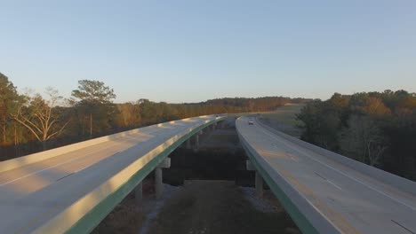 cars driving on rural two lane road bridge over small river